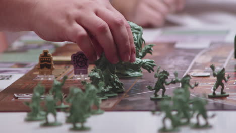 hand moving green characters or figures on desk game, closeup view of next turn