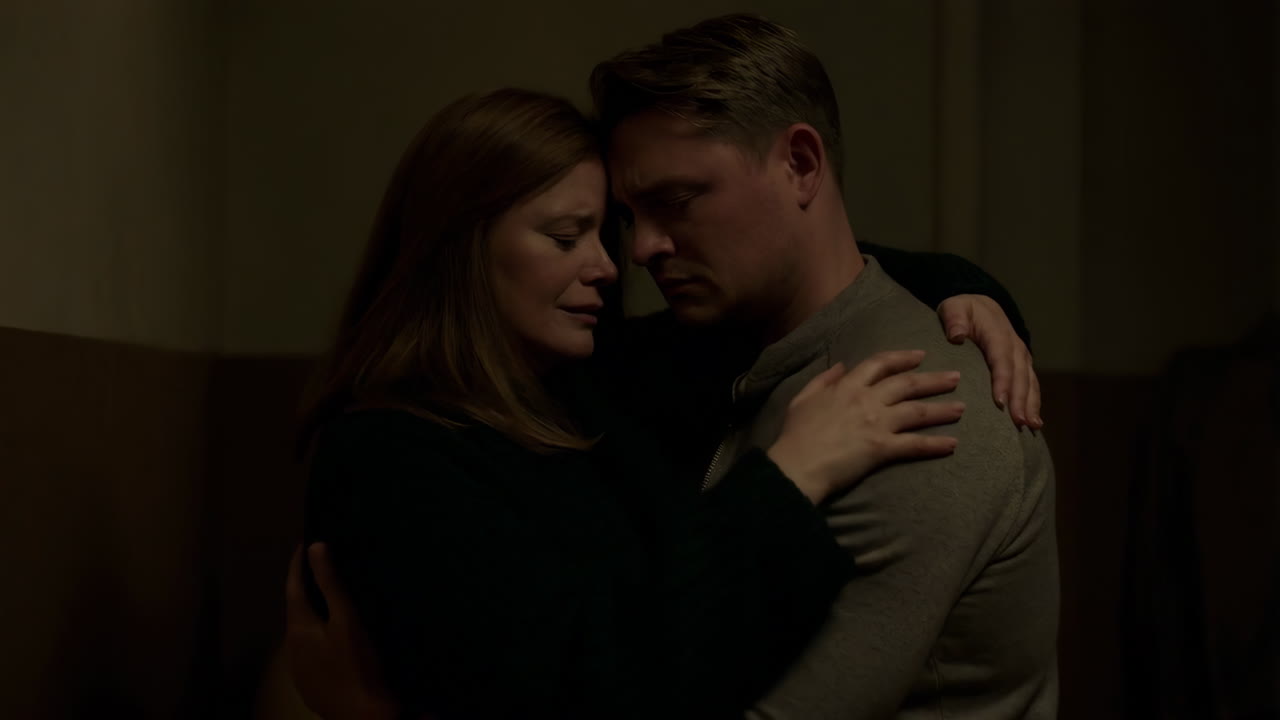A couple shares a comforting embrace in a dimly lit setting