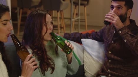 close up of friends at home or in bar celebrating at st patrick's day party drinking alcohol and eating popcorn