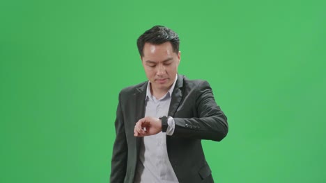 asian business man walking while looking at watch and run on green screen chroma key