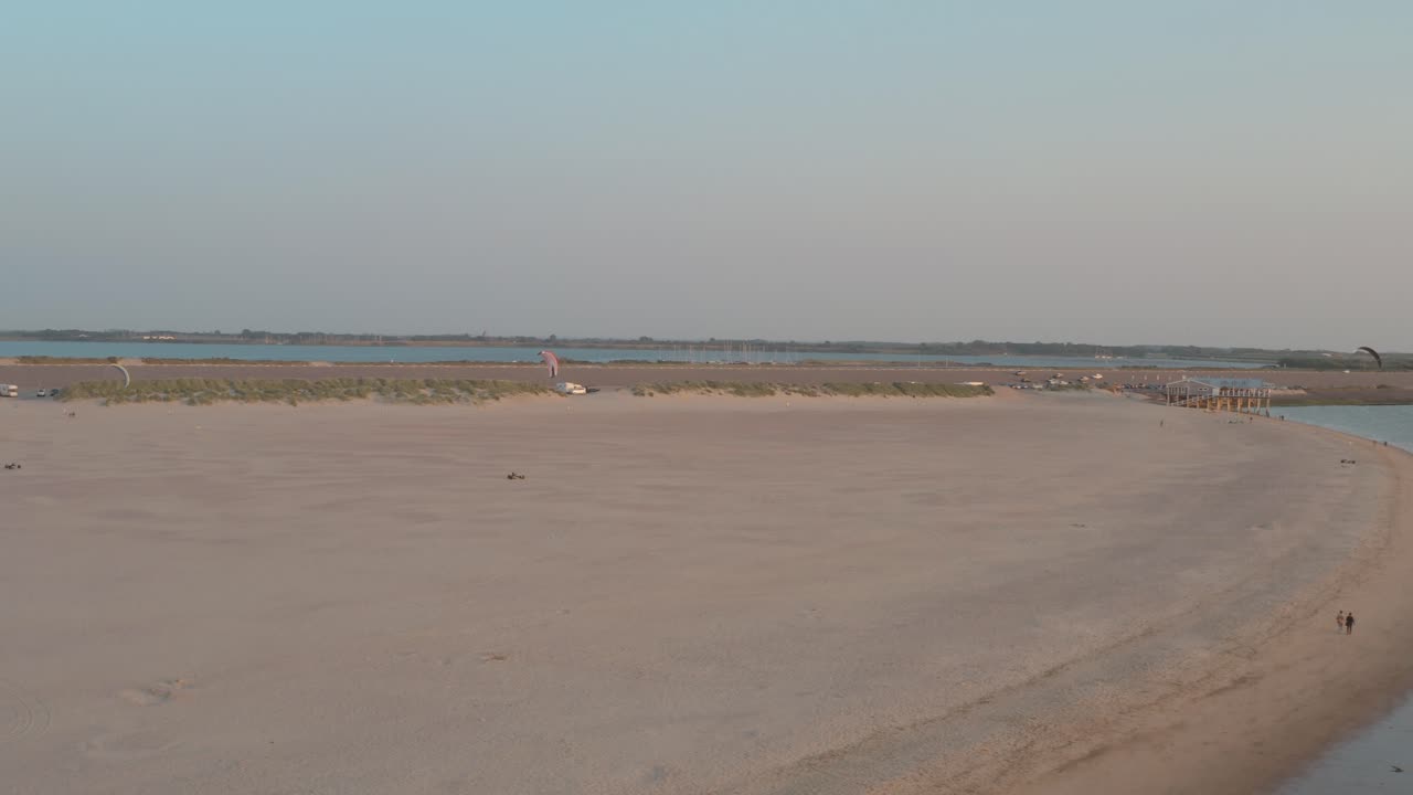 dron cinemático: panorama aéreo que rodea la playa natural verde y arenosa al atardecer con turistas y personas con buggykiting en zelanda en el mar del norte, países bajos, 25p