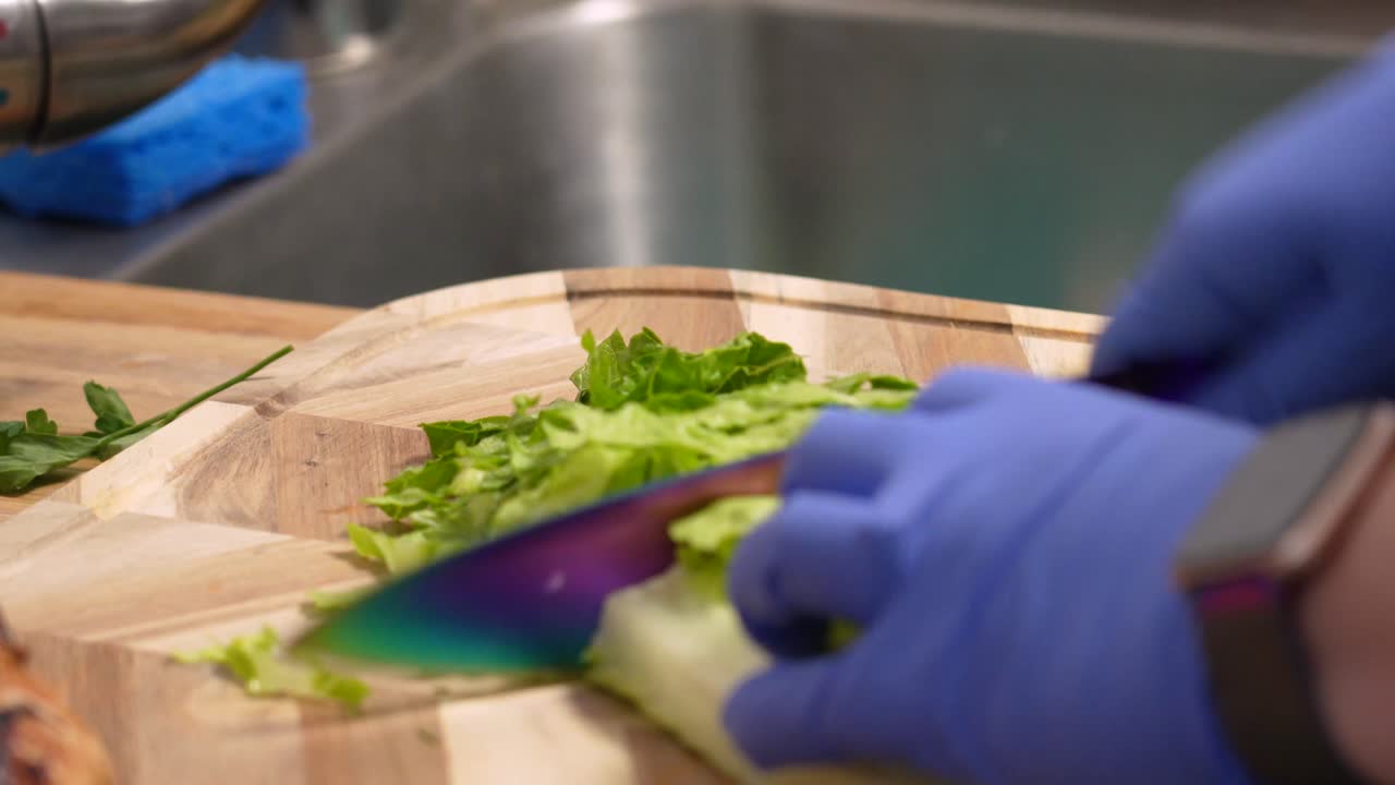 Hands Wearing Rubber Gloves With Fresh Lettuce Cut Into Shreds At Wooden Board. - Closeup Shot