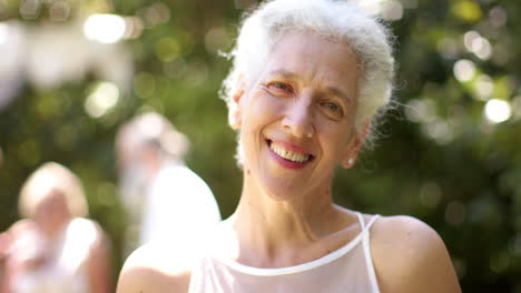 smiling senior bride enjoying outdoor gathering with friends in background