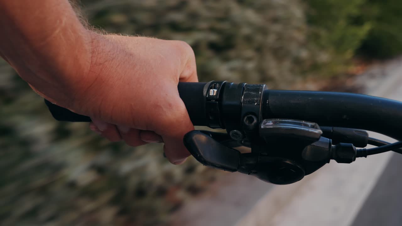 A hand holding the handlebar of a bicycle