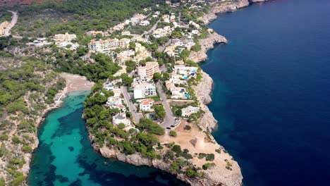 seaside town of torrent de cala pi with beach inlet near by on mallorca spain, aerial dolly out shot