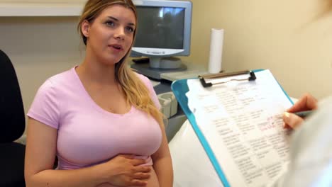 médico tomando notas de una paciente embarazada