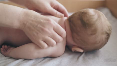 newborn-boy-lies-on-stomach-and-nurse-makes-massage