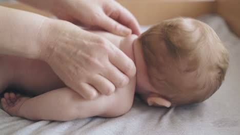 newborn boy lies on stomach and nurse makes massage