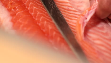 itamae chef with a great cutting skills slicing thinly the meat of a salmon fish for sushi dish