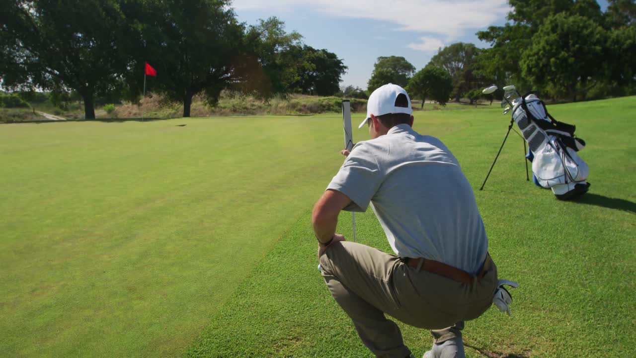 Golfista maschio caucasico inginocchiato su un campo da golf in una giornata di sole