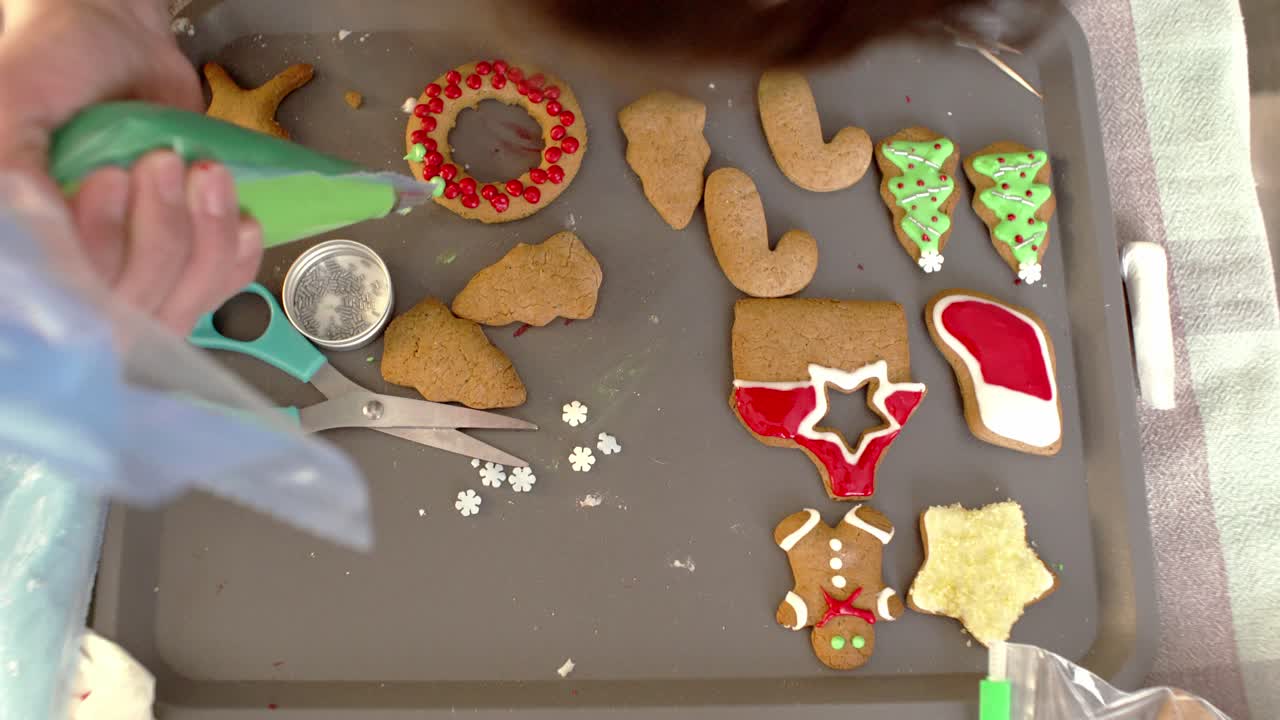 glaseado y decoración de galletas navideñas de pan de jengibre, usando una manga pastelera con glaseado de azúcar coloreado 4k, vista alta