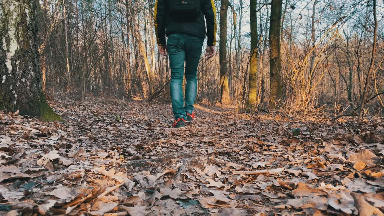 Man walking past and away from the camera during a sunset in the forest