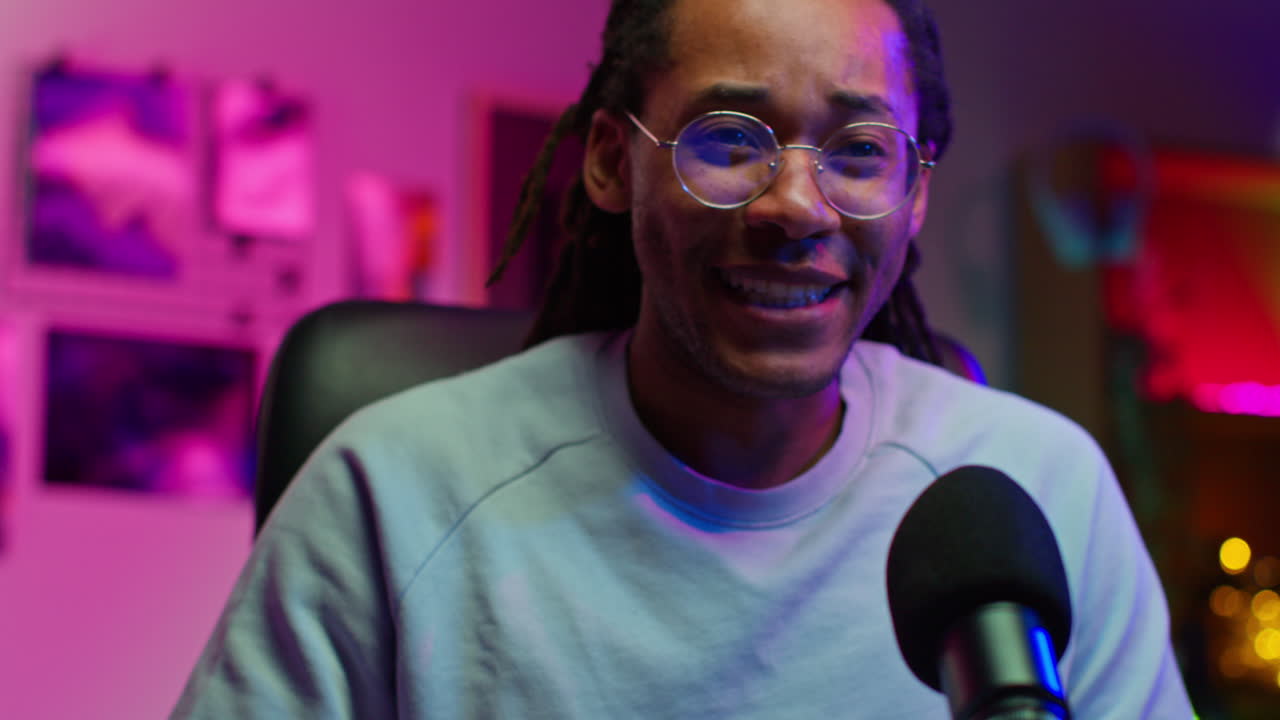 Man with dreadlocks and glasses recording a podcast or a stream