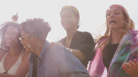 group of young friends dancing behind barrier at outdoor music festival