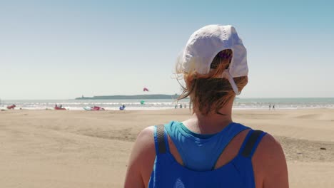chica turista viendo una playa llena de kitesurf en un día soleado, marruecos