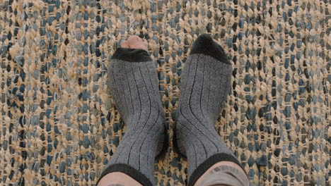 top-view-feet-wearing-broken-socks-toes-wiggling-dancing-at-home-on-carpet-rug