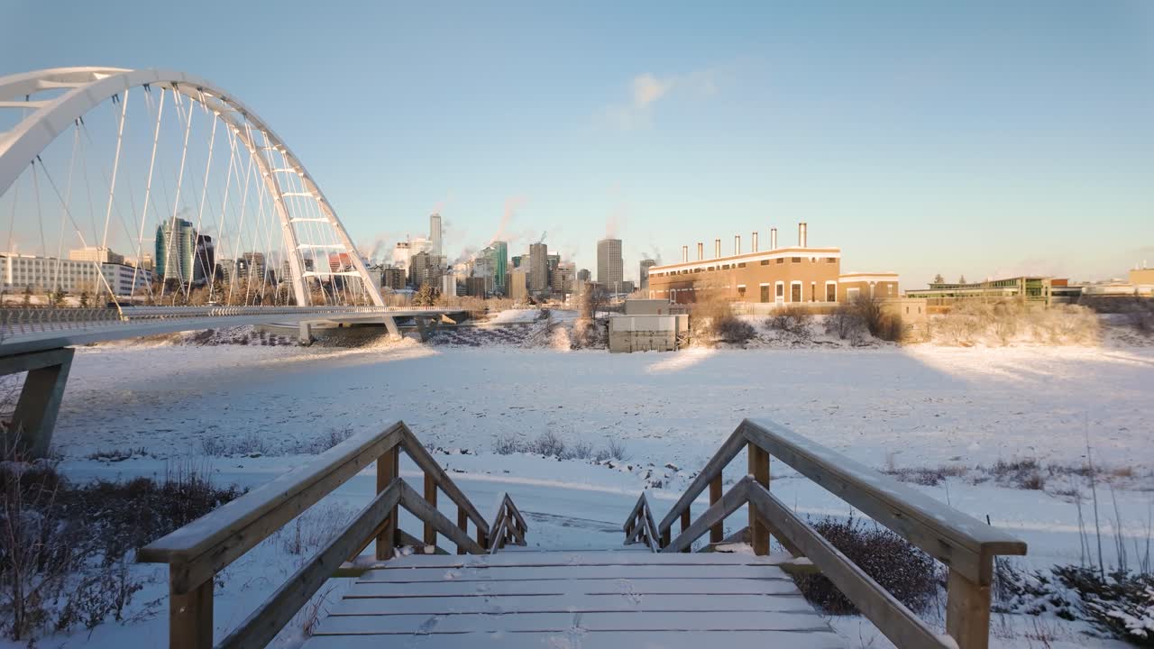 Downtown Edmonton, viewed from the Walterdale Bridge, showcasing Highrise buildings, a snowy river valley, and the cold beauty of the city