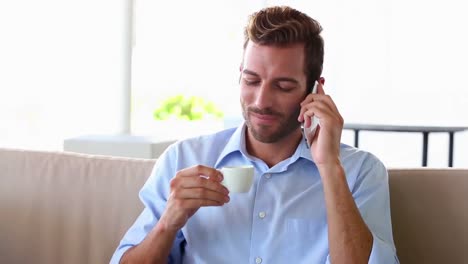 Businessman-talking-on-phone-and-drinking-espresso