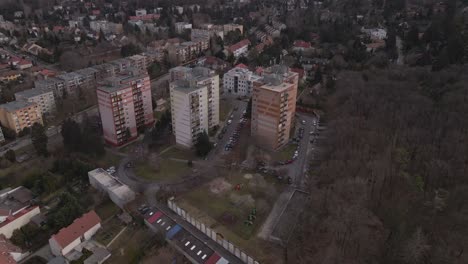 an aerial view of three residential apartment buildings surrounded by greenery and a nearby forest.
