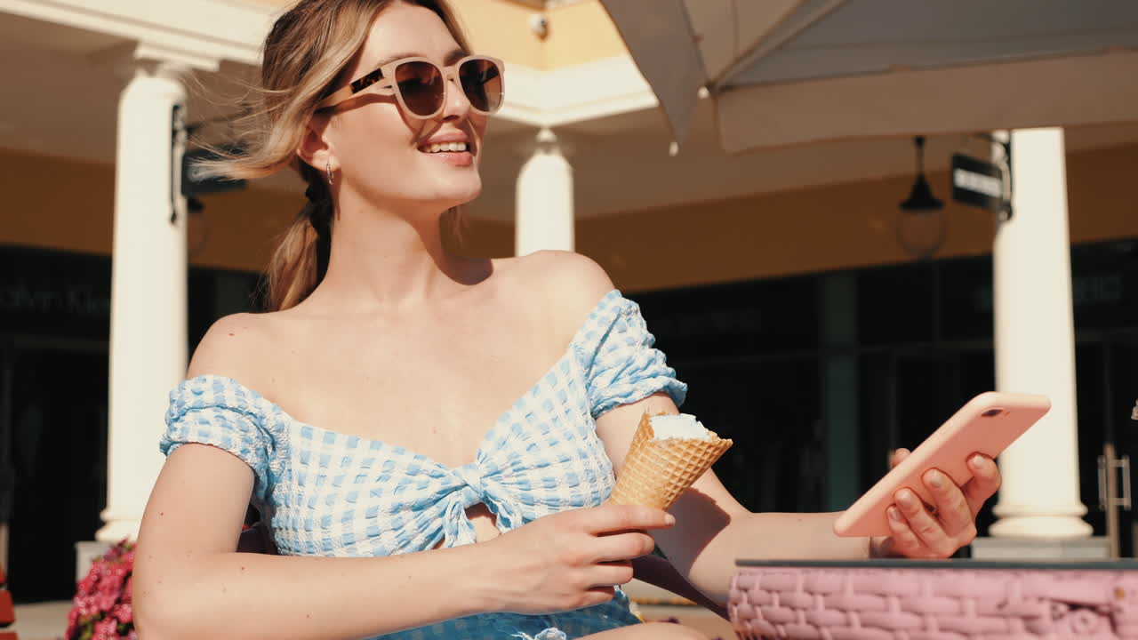 아이스크림을 즐기고 카페에서 전화를 사용하는 여자