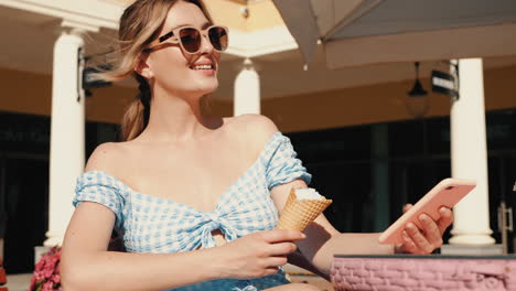 woman enjoying ice cream and using phone in a cafe