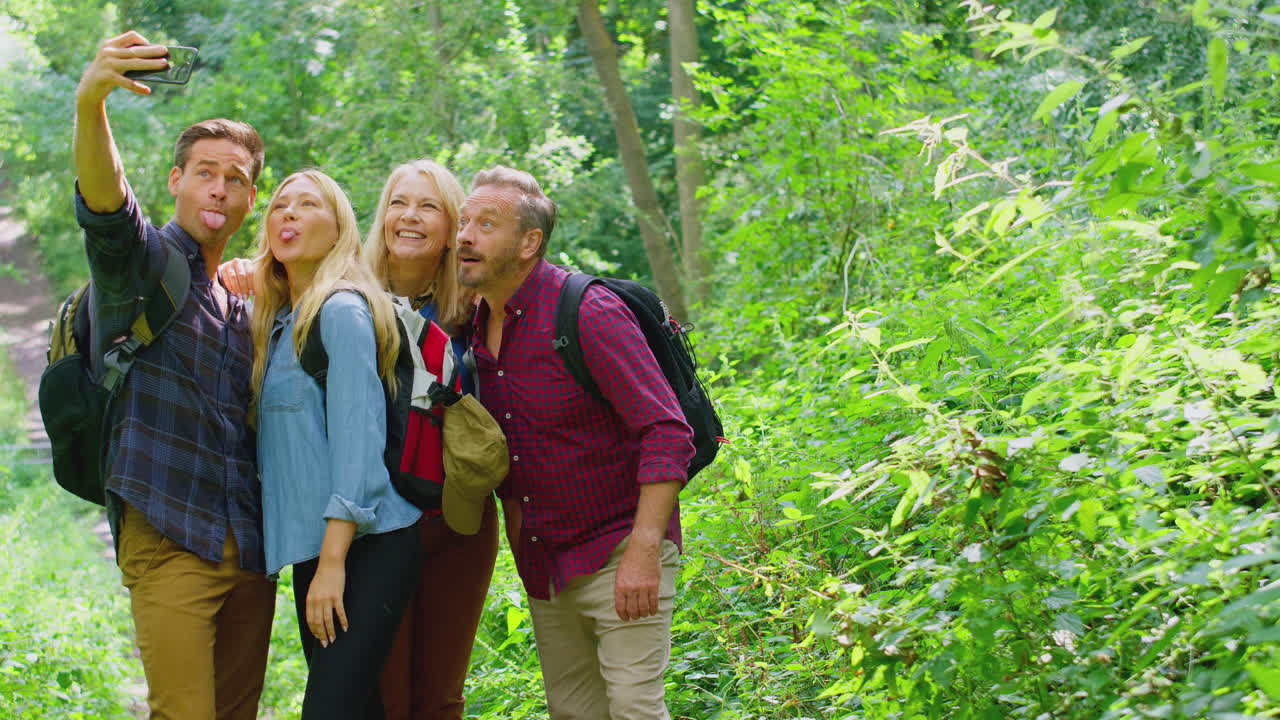 Gruppo di amici in posa per un selfie in campagna, che scattano una foto con il telefono mentre fanno un'escursione lungo un sentiero.