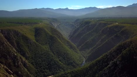 hermoso puente panorámico de bloukrans que se eleva sobre el río - valle, áfrica, retroceso aéreo revela movimiento