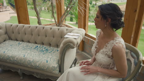 Overhead shot of a bride sitting elegantly next to a white sofa, with natural light entering through a large window.