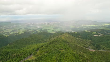 Lagoa-do-fogo-with-lush-green-mountains-and-distant-ocean,-aerial-view