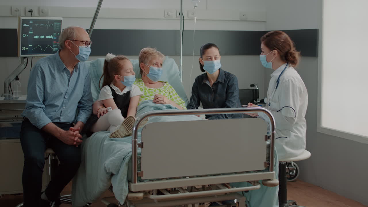 Medic explaining diagnosis to aged patient and visitors in hospital ward