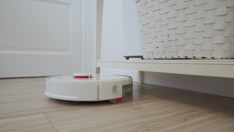 white robot vacuum cleaner performs automatic cleaning of the apartment, modern technology of smart cleaning.