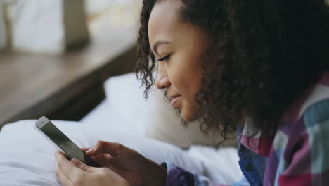 mujer joven usando teléfono inteligente en la cama