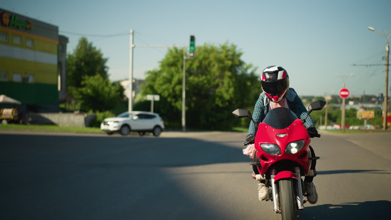 두 명의 여성이 헬을 착용하여 전력 자전거를 타고 부드러운 타르 도로를 항해하는 동안 바람이 그들의 옷을 뒤로 불어넣고, suv 자동차는 신호판과 함께 천천히 배경에 구부러집니다.