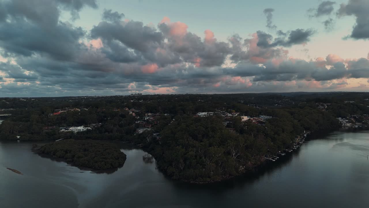 Aerial of Georges River near Oatley with forested shores, still waters and moody sky at dusk, establishing overview
