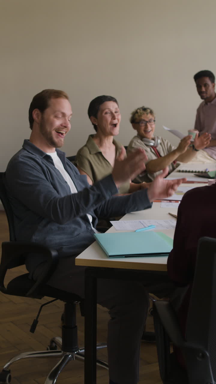 A diverse group of business professionals clapping and celebrating in a meeting
