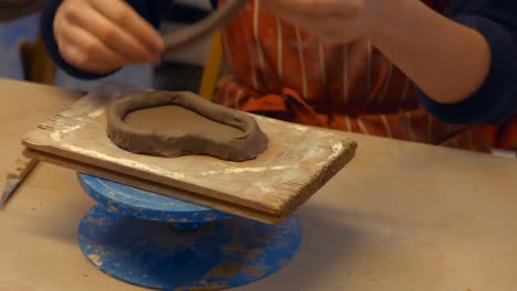 hands of male potter assisting female potter