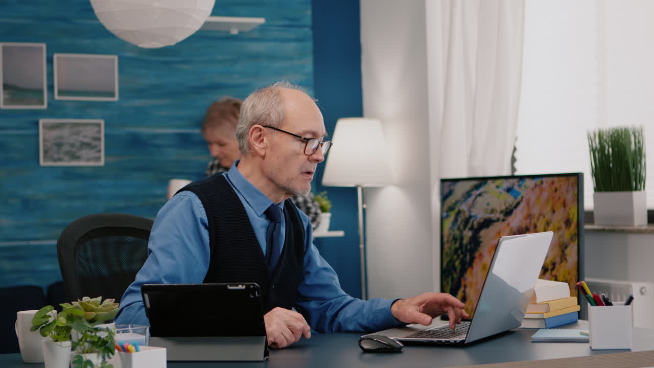 Senior man using laptop and tablet in same time