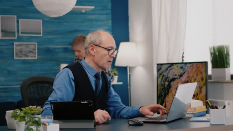 senior man using laptop and tablet in same time