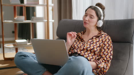 Eine-Lächelnde-Europäische-Frau-Mit-Kopfhörern-Und-Laptop-Auf-Dem-Schoß-Führt-Einen-Videoanruf