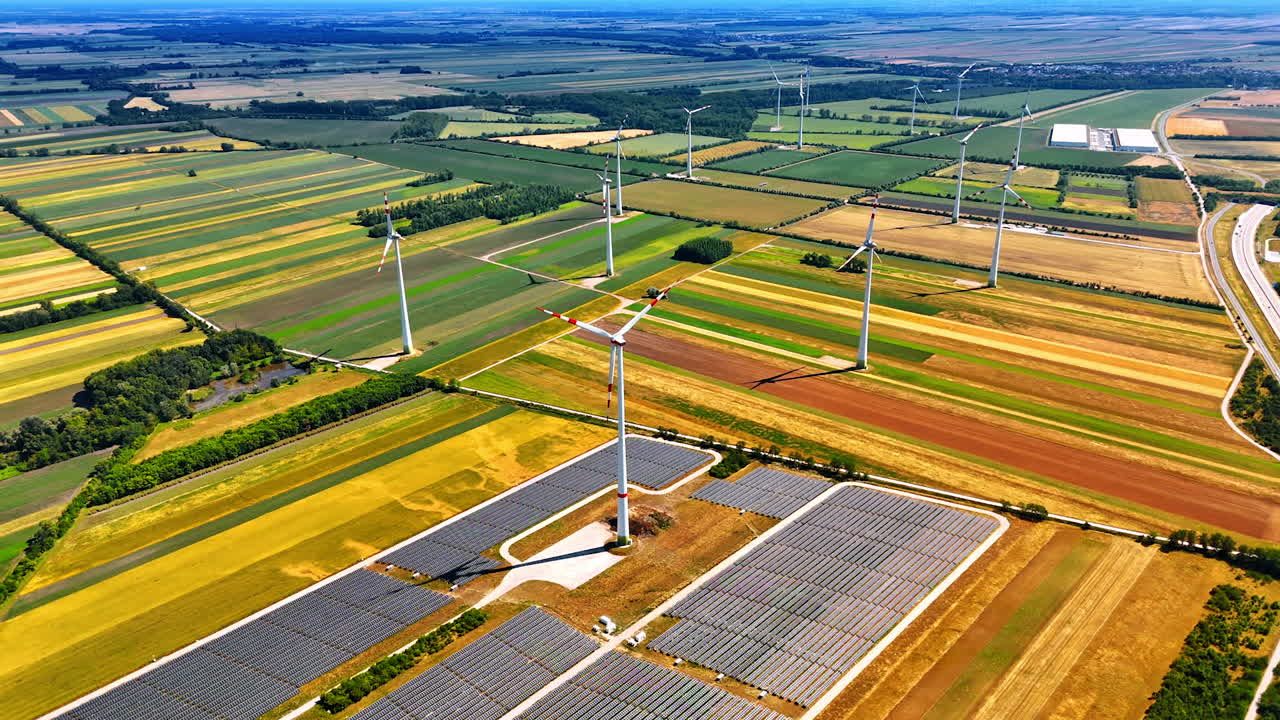 Spectacular colorful fields with installed wind turbines. Solar panel site is located nearby. Aerial view