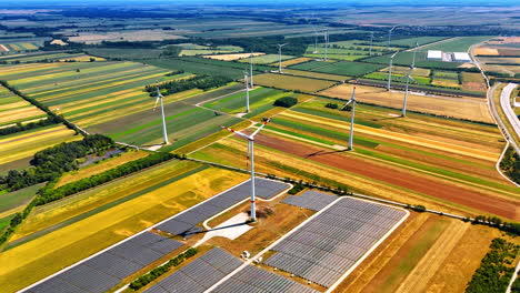 spectacular colorful fields with installed wind turbines. solar panel site is located nearby. aerial view