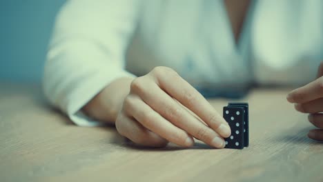 female hand of a woman, dressed in white business suit destroying blocks of dominos, that are falling