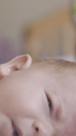 restless infant boy with blond hair lies on changing table and nurse practices massage extreme close view