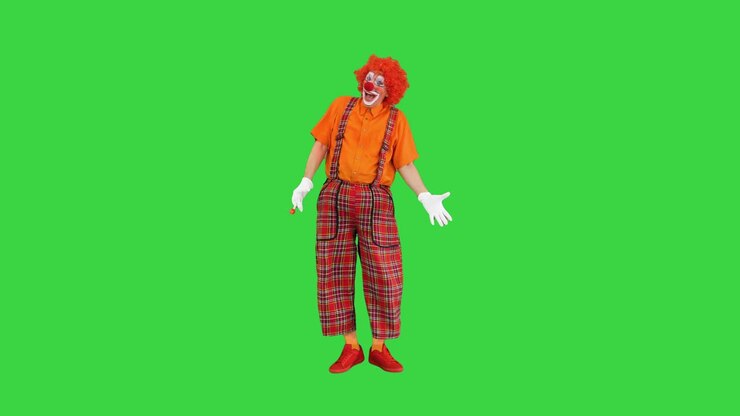 Clown con naso rosso che soffia in una trombetta da festa su green screen, chroma key.