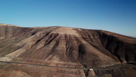 paisaje escarpado y estéril con un camino sinuoso en fuerteventura, islas canarias, bajo un cielo despejado, vista aérea