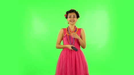 woman with tv remote in her hand, switching on tv and very laughs. green screen