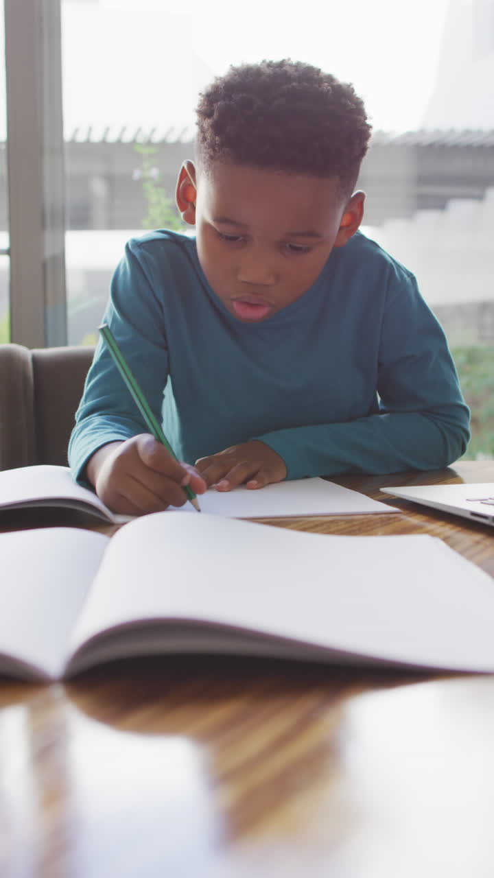 video vertical de un niño afroamericano haciendo la tarea