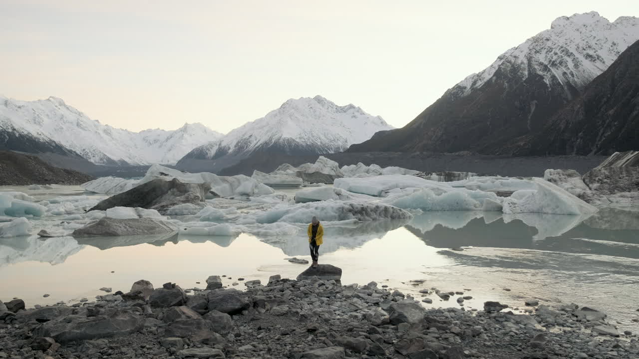 Kvinde står midt i Tasman Lake i New Zealand