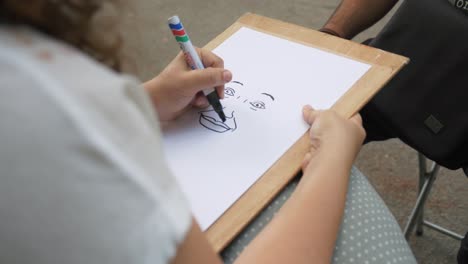 girl drawing face of a man in the park