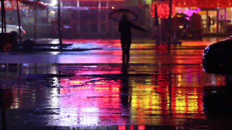 cinemagraph of a woman in the evening on a road staying still with an umbrella while it is raining